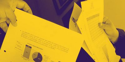 A close-up of hands holding yellow-tinted documents featuring a bar chart and a pie graph.